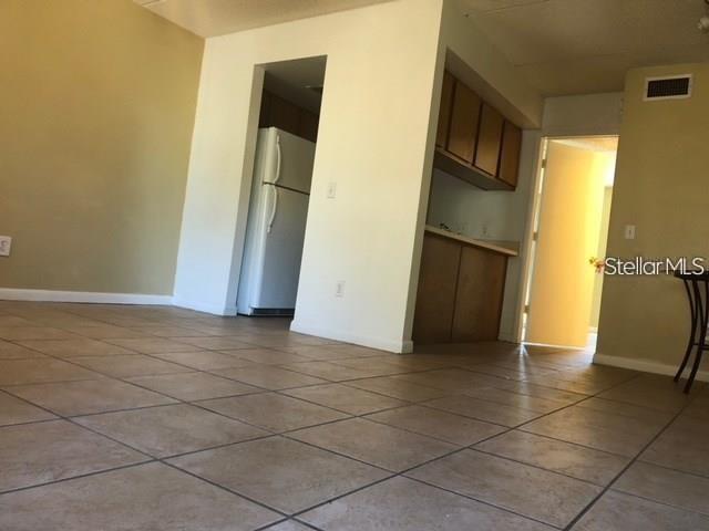 A view of a tiled living area looking toward a kitchen with wood cabinets — 4922 W GANDY BOULEVARD UNIT 102, TAMPA, FL