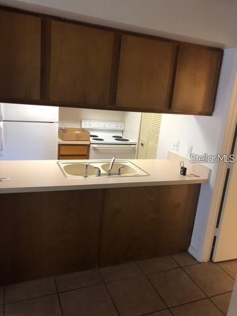A kitchen features wood cabinets, a white countertop, and a double-basin sink — 4922 W GANDY BOULEVARD UNIT 102, TAMPA, FL