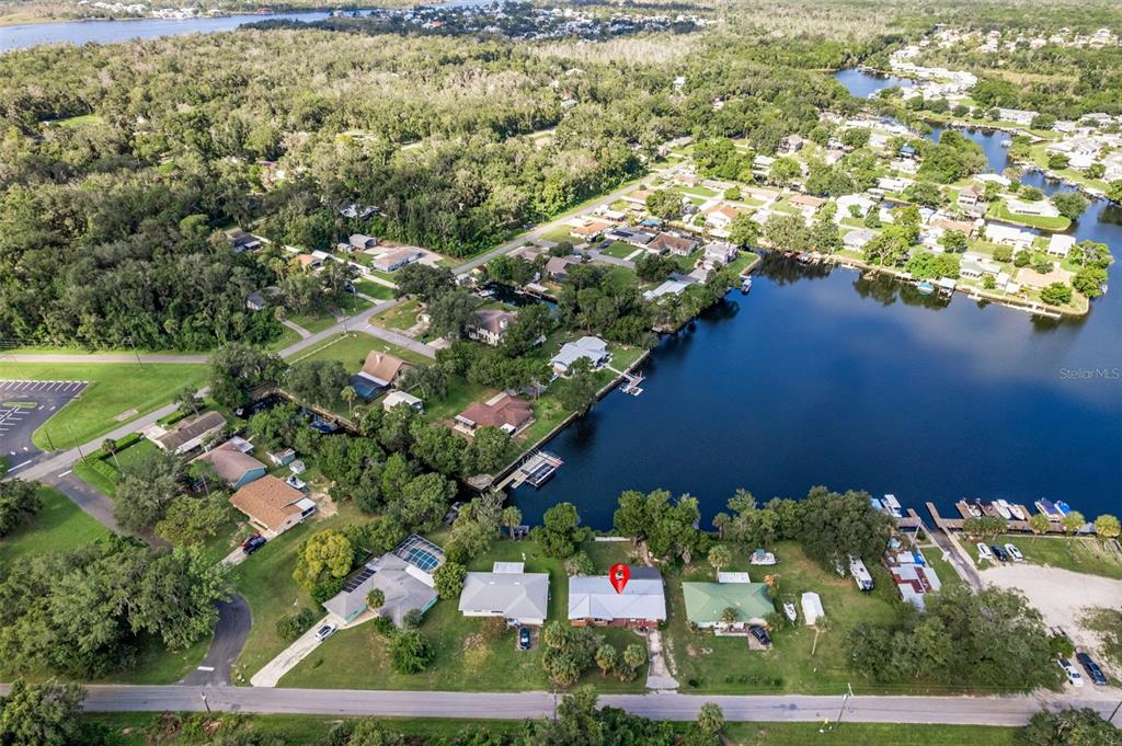 An aerial view shows a residential neighborhood with houses situated along a waterfront canal — 3902 N TALLAHASSEE ROAD, CRYSTAL RIVER, FL