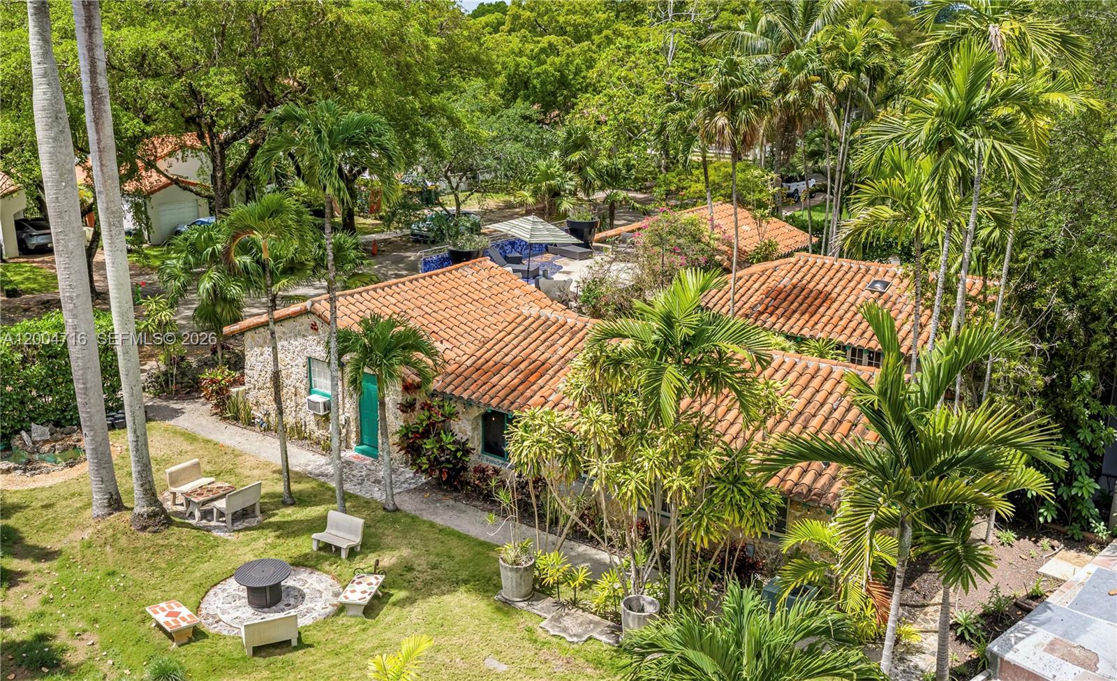 An aerial view shows a stone house with a terracotta roof surrounded by lush landscaping — 1301 Milan Ave, Coral Gables FL 33134, CORAL GABLES, FL