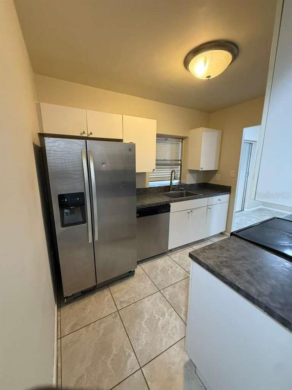 A kitchen features stainless steel appliances, white cabinets, and gray countertops over tiled floors — 22189 LARAMORE AVENUE, PORT CHARLOTTE, FL