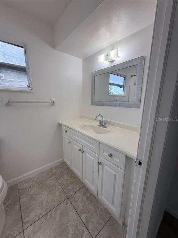 A bathroom features a white vanity with a sink, a mirror, and tiled flooring — 22189 LARAMORE AVENUE, PORT CHARLOTTE, FL