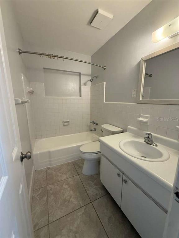 A bathroom features a white vanity, a toilet, and a tiled bathtub shower combination — 22189 LARAMORE AVENUE, PORT CHARLOTTE, FL