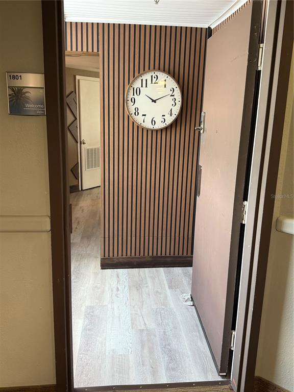 A doorway opens into a room featuring wood-slat wall paneling and a large wall clock — 6165 CARRIER DRIVE UNIT 1801, ORLANDO, FL