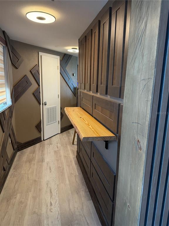 A hallway features dark wood paneling, a live-edge wood shelf, and light-colored wood-look flooring — 6165 CARRIER DRIVE UNIT 1801, ORLANDO, FL