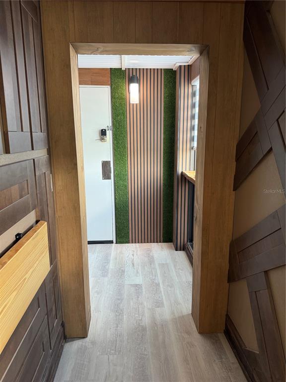 A doorway leads to a room with wood-paneled walls, artificial grass accents, and light flooring — 6165 CARRIER DRIVE UNIT 1801, ORLANDO, FL