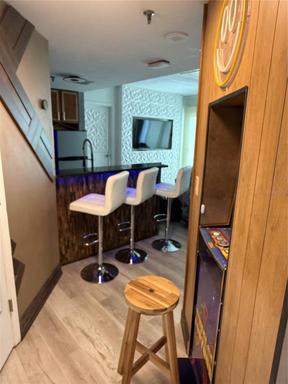 A home bar area features three white bar stools, a wood-paneled counter, and a television — 6165 CARRIER DRIVE UNIT 1801, ORLANDO, FL