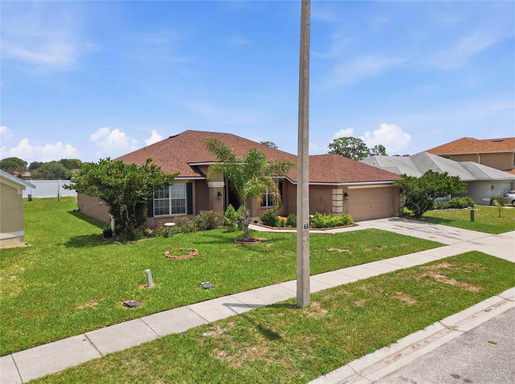 A single-story suburban house with a brown roof, tan stucco exterior, and a front lawn — 1097 NORMANDY HEIGHTS CIRCLE, WINTER HAVEN, FL