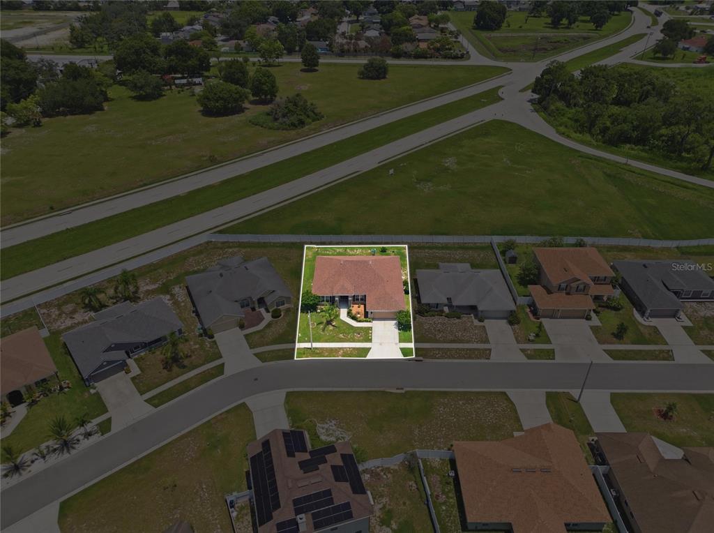 An aerial view shows a single-story house with a brown roof and a concrete driveway — 1097 NORMANDY HEIGHTS CIRCLE, WINTER HAVEN, FL