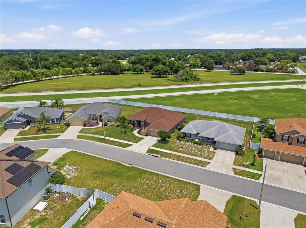 An aerial view shows a suburban neighborhood street with several single-family homes and a large field — 1097 NORMANDY HEIGHTS CIRCLE, WINTER HAVEN, FL