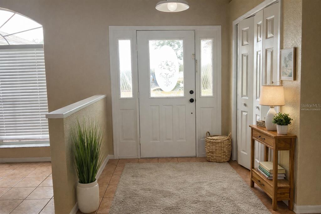 An entryway features a white front door with sidelights, tile flooring, and a small console table — 11018 AUDIE BROOK DRIVE, SPRING HILL, FL