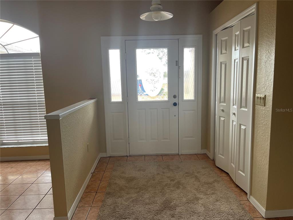 An entryway features a white front door with sidelights, tile flooring, and a closet — 11018 AUDIE BROOK DRIVE, SPRING HILL, FL