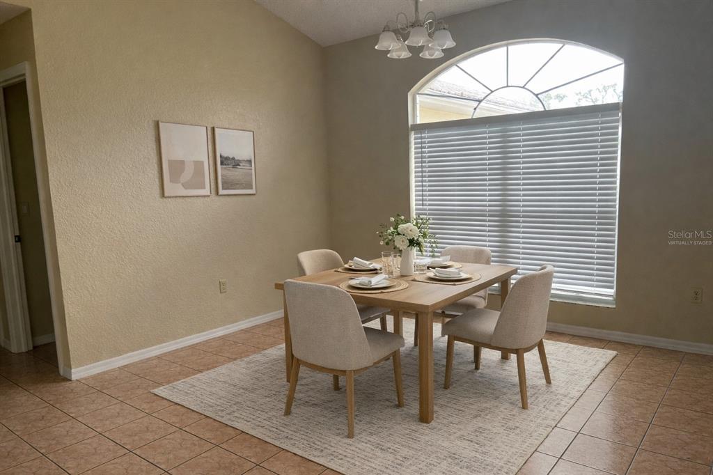 A dining room features a wooden table with four chairs, a rug, and an arched window — 11018 AUDIE BROOK DRIVE, SPRING HILL, FL