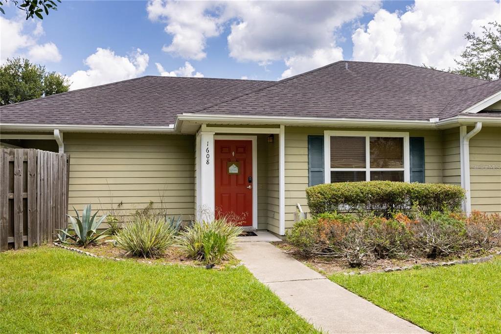 A single-story house with light green siding, a red front door, and a dark roof — 1608 NE 45TH PLACE, GAINESVILLE, FL