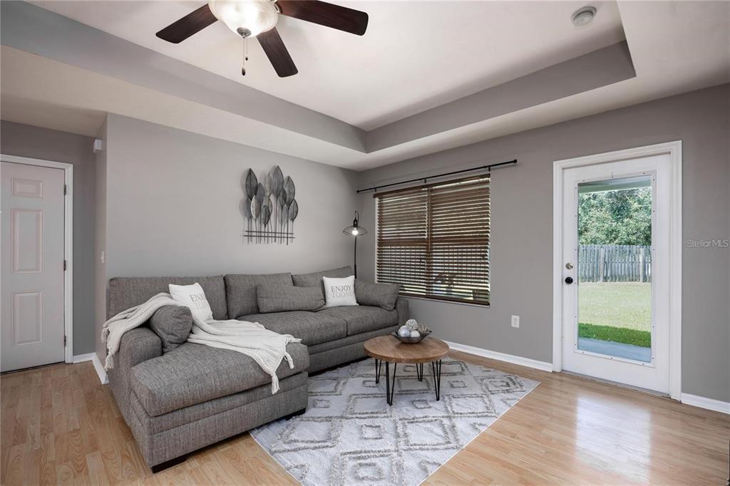 A living room features a gray sectional sofa, a round coffee table, and a glass door — 1608 NE 45TH PLACE, GAINESVILLE, FL