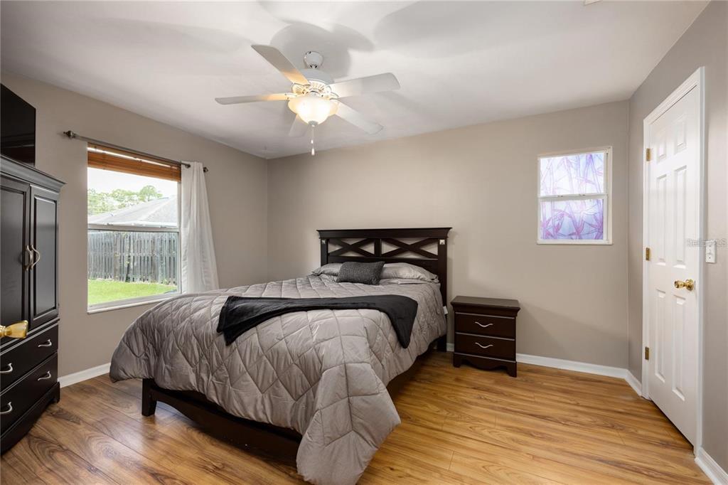 A bedroom features wood-look flooring, a dark wood bed frame, and a ceiling fan — 1608 NE 45TH PLACE, GAINESVILLE, FL