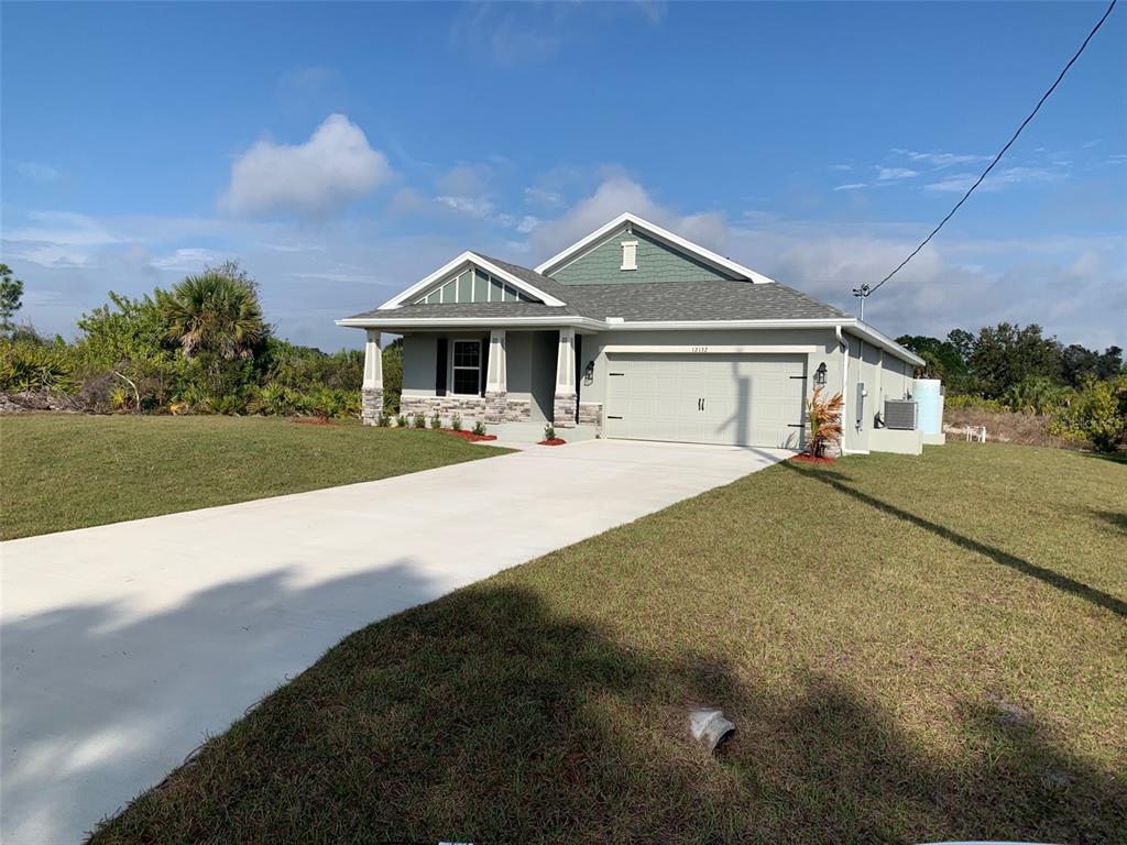 A single-story house with a two-car garage, stone accents, and a light-colored driveway — 12132 BACCHUS ROAD, PORT CHARLOTTE, FL