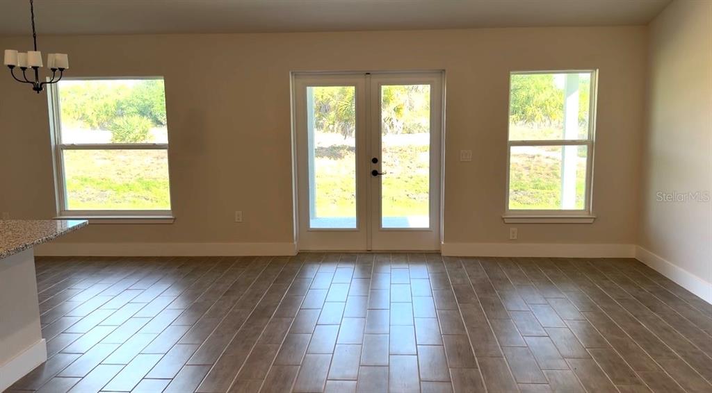 A dining area features tile flooring, a chandelier, two windows, and a set of French doors — 12132 BACCHUS ROAD, PORT CHARLOTTE, FL