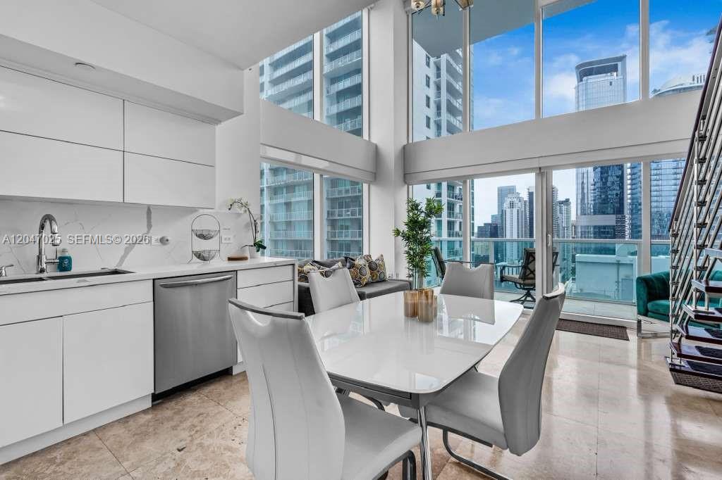 A modern kitchen and dining area features white cabinetry, floor-to-ceiling windows, and city views — 41 SE 5th St # 1702, Miami FL 33131, MIAMI, FL