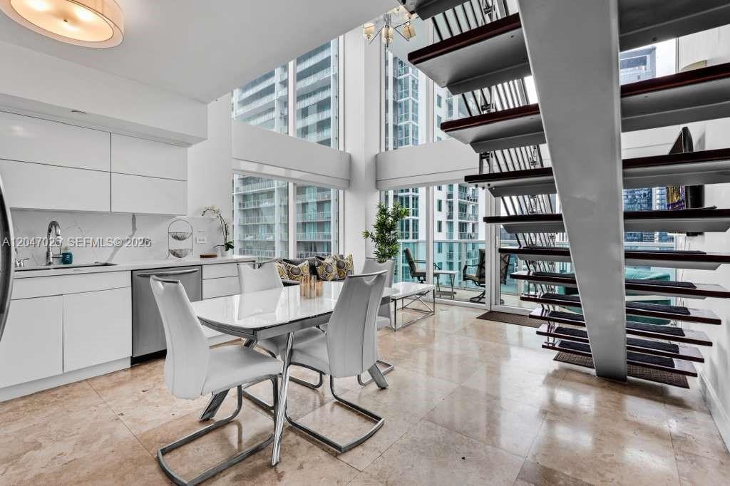 A modern dining area features a white table, four chairs, and a floating staircase — 41 SE 5th St # 1702, Miami FL 33131, MIAMI, FL