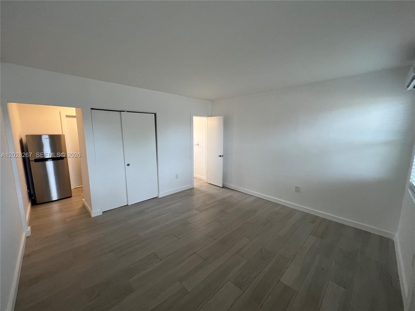 An empty room features light wood-look tile flooring, white walls, a closet, and an open doorway — 7035 NE 4th Ct # 3, Miami FL 33138, MIAMI, FL