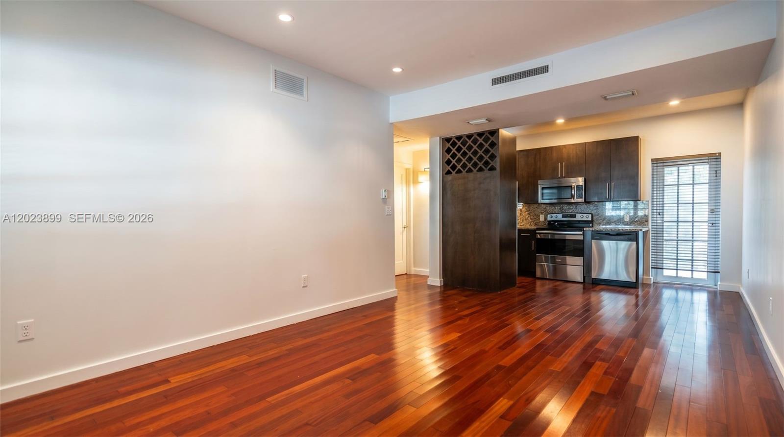 This room features dark hardwood floors, a kitchen with stainless steel appliances, and wine storage — 1438 Meridian Ave, Miami Beach FL 33139, MIAMI BEACH, FL