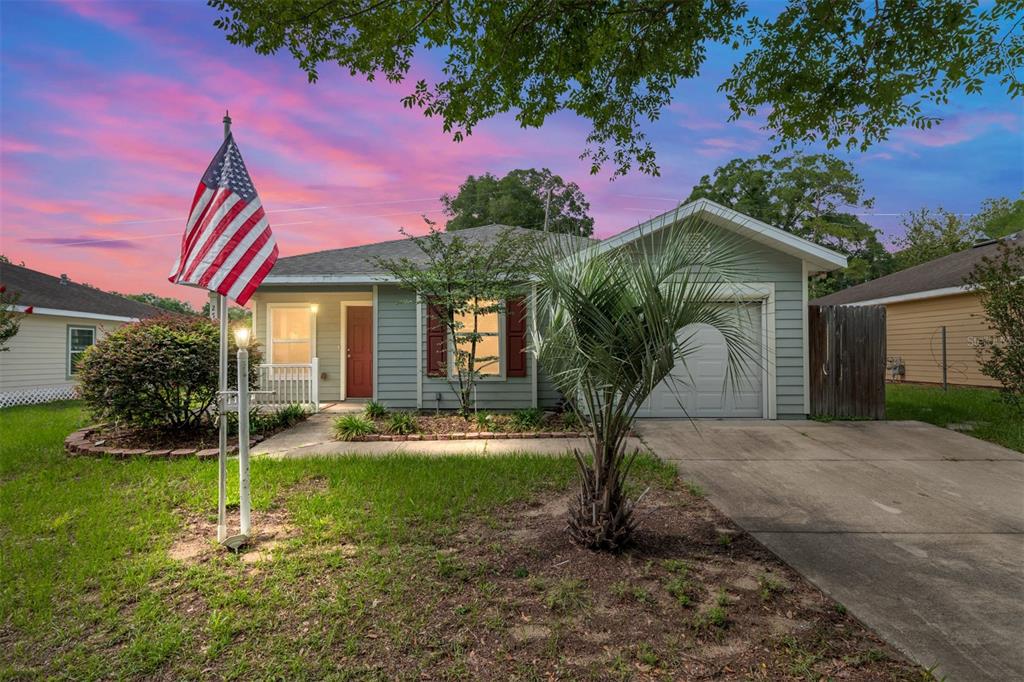 A single-story house with light green siding, a red front door, and an American flag — 2776 SE 21ST ROAD, GAINESVILLE, FL