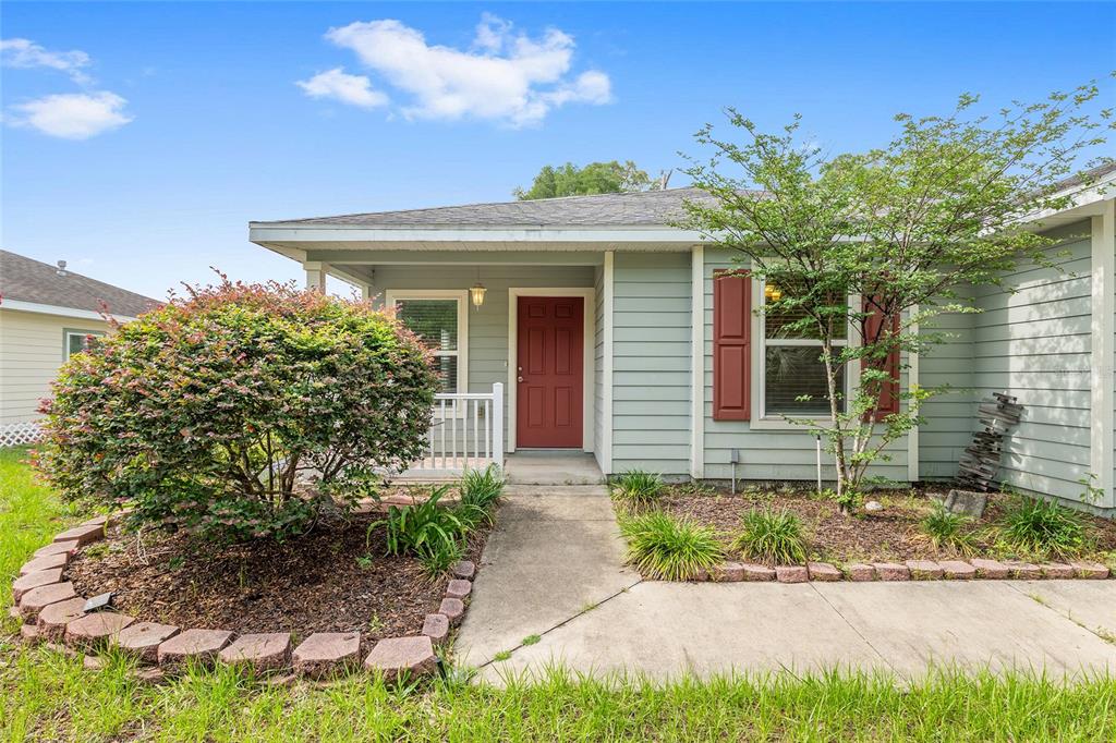 A single-story house with light green siding, a red front door, and a concrete walkway — 2776 SE 21ST ROAD, GAINESVILLE, FL