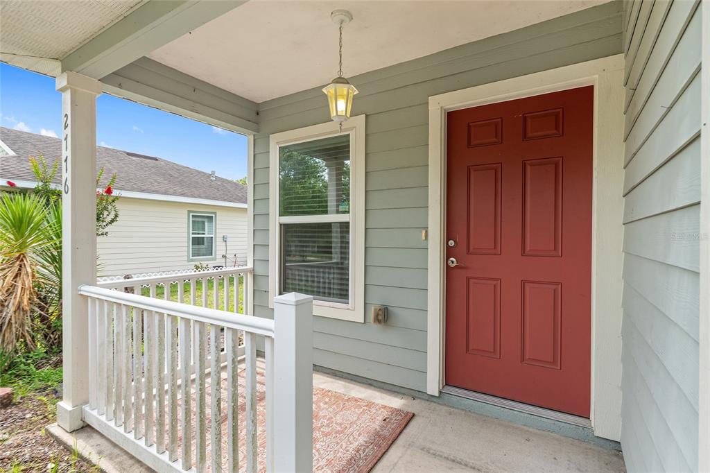 A covered front porch features a red door, light green siding, and a white railing — 2776 SE 21ST ROAD, GAINESVILLE, FL