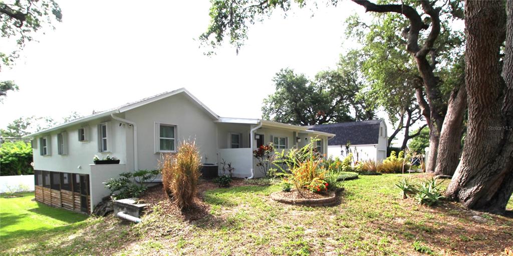 A white house with a screened porch and a detached garage sits among large trees — 2436 NAVAREZ AVENUE, SAFETY HARBOR, FL