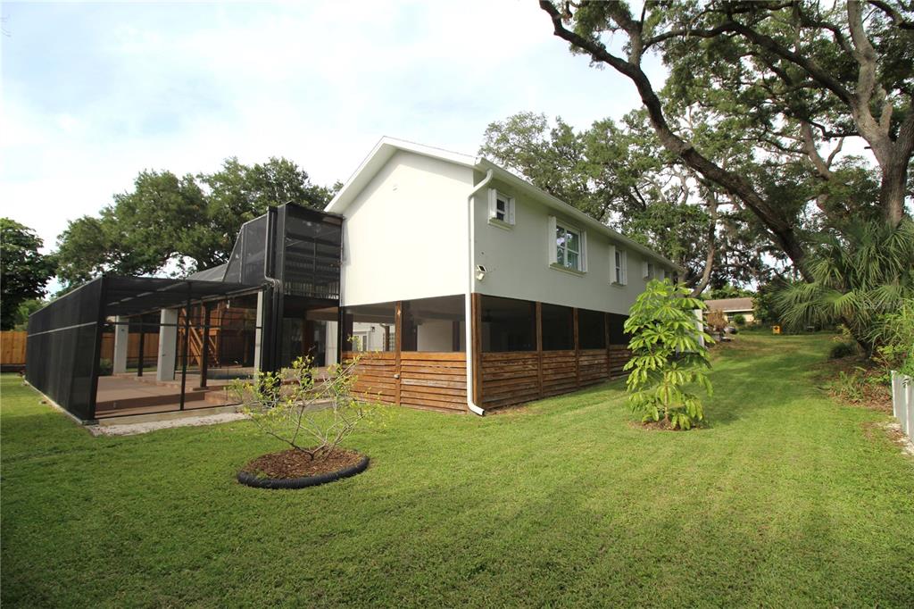 A two-story house with a screened-in porch and pool enclosure sits on a grassy lawn — 2436 NAVAREZ AVENUE, SAFETY HARBOR, FL