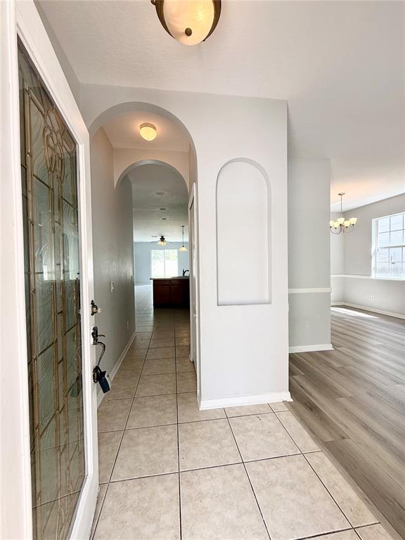An entryway with tiled flooring leads to an arched hallway and a living area — 20216 STILL WIND DRIVE, TAMPA, FL