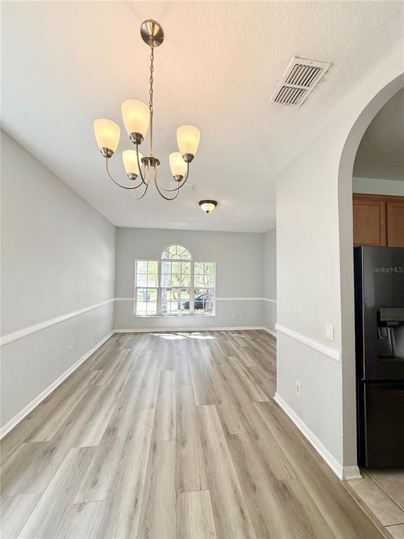 A dining area features light gray walls, wood-look flooring, and a central chandelier — 20216 STILL WIND DRIVE, TAMPA, FL
