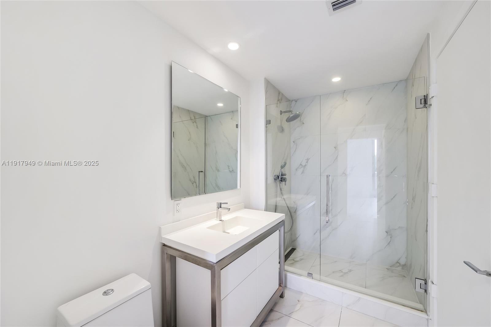 A modern bathroom features a white vanity, a large mirror, and a glass-enclosed marble shower — 2000 Metropica Way # 306, Sunrise FL 33323, SUNRISE, FL