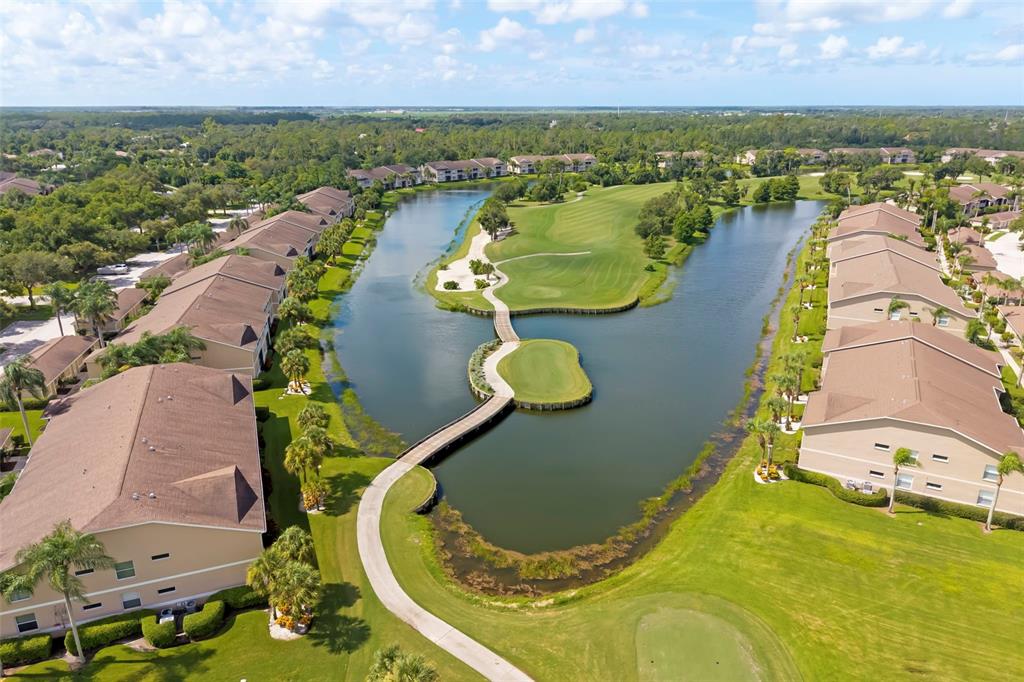 An aerial view shows a golf course green surrounded by water with a pedestrian bridge — 5220 HYLAND HILLS AVENUE UNIT 1226, SARASOTA, FL
