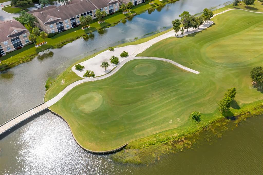 An aerial view shows a golf course green surrounded by water and a wooden bridge — 5220 HYLAND HILLS AVENUE UNIT 1226, SARASOTA, FL