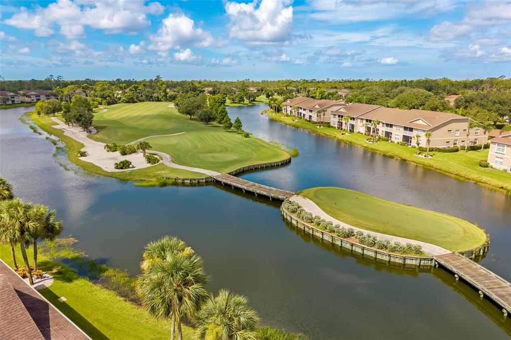 An aerial view shows a golf course green surrounded by water with a wooden footbridge — 5220 HYLAND HILLS AVENUE UNIT 1226, SARASOTA, FL