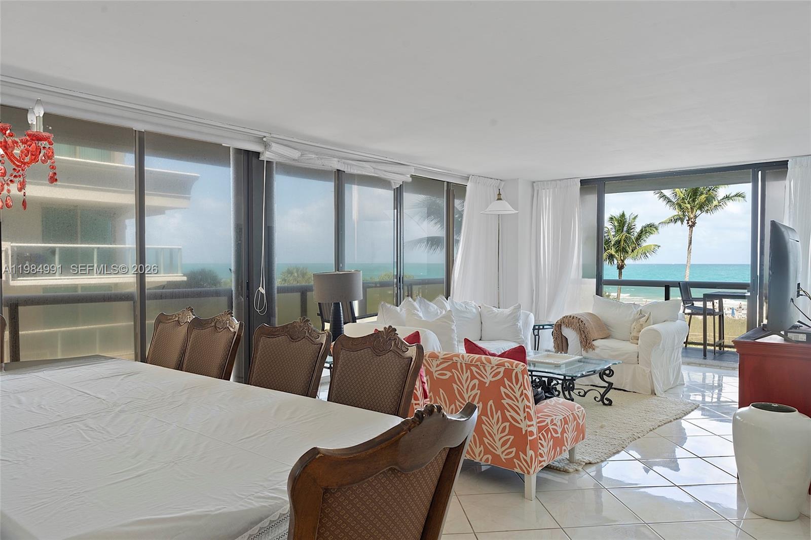 A bright living and dining area features tile floors, ocean views, and a red chandelier — 9455 Collins Ave # 409, Surfside FL 33154, SURFSIDE, FL