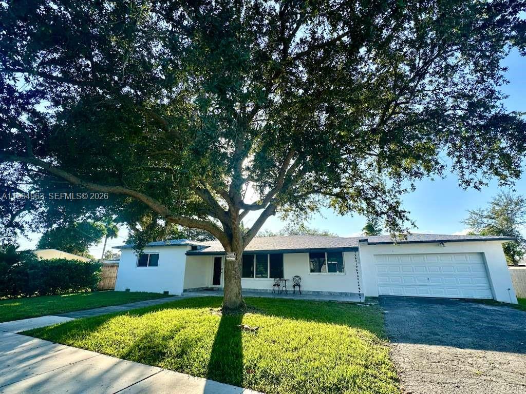 A single-story white house with a large tree in the front yard and a garage — 628 SW 6th Ave, Hallandale Beach FL 33009, HALLANDALE BEACH, FL