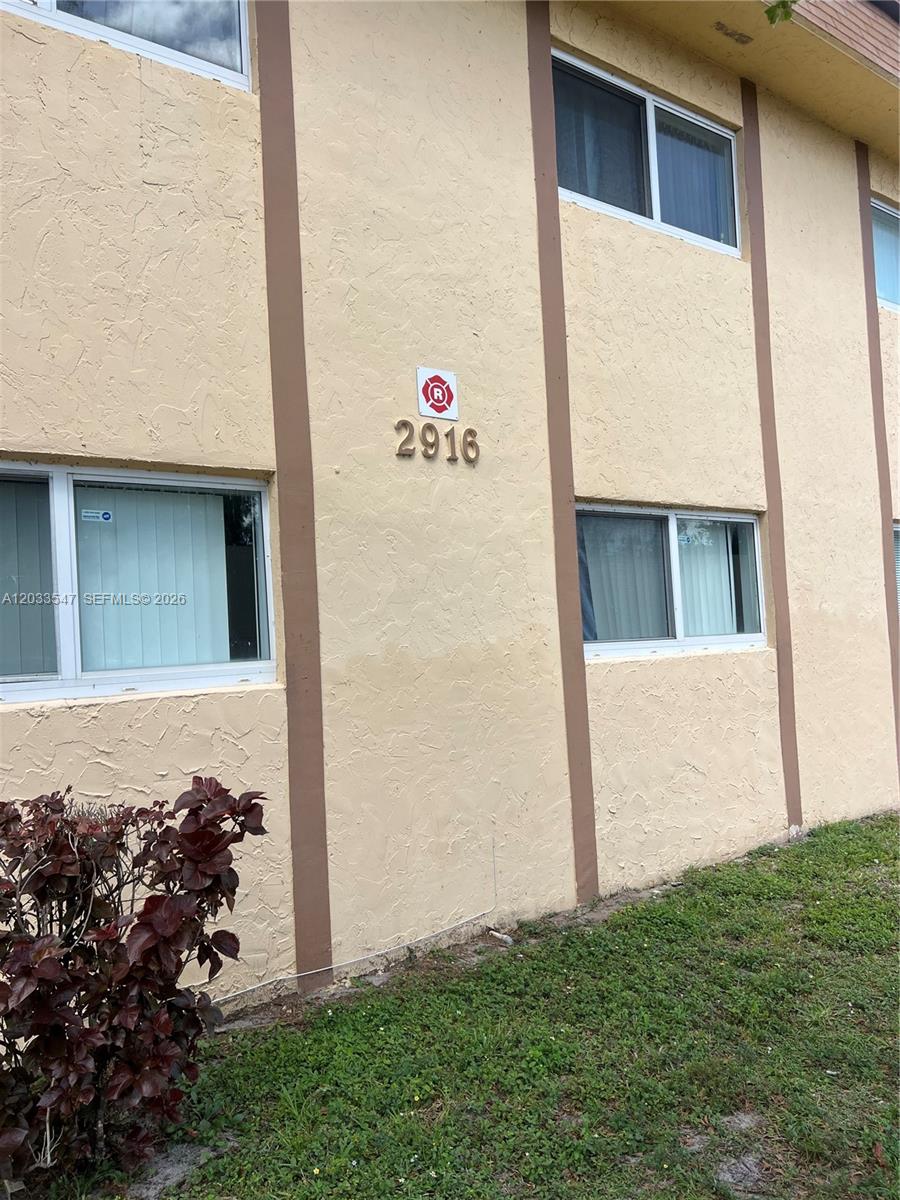 The exterior of a two-story stucco building features brown vertical trim and window units — 2916 NW 55th Ave # 2A, Lauderhill FL 33313, LAUDERHILL, FL