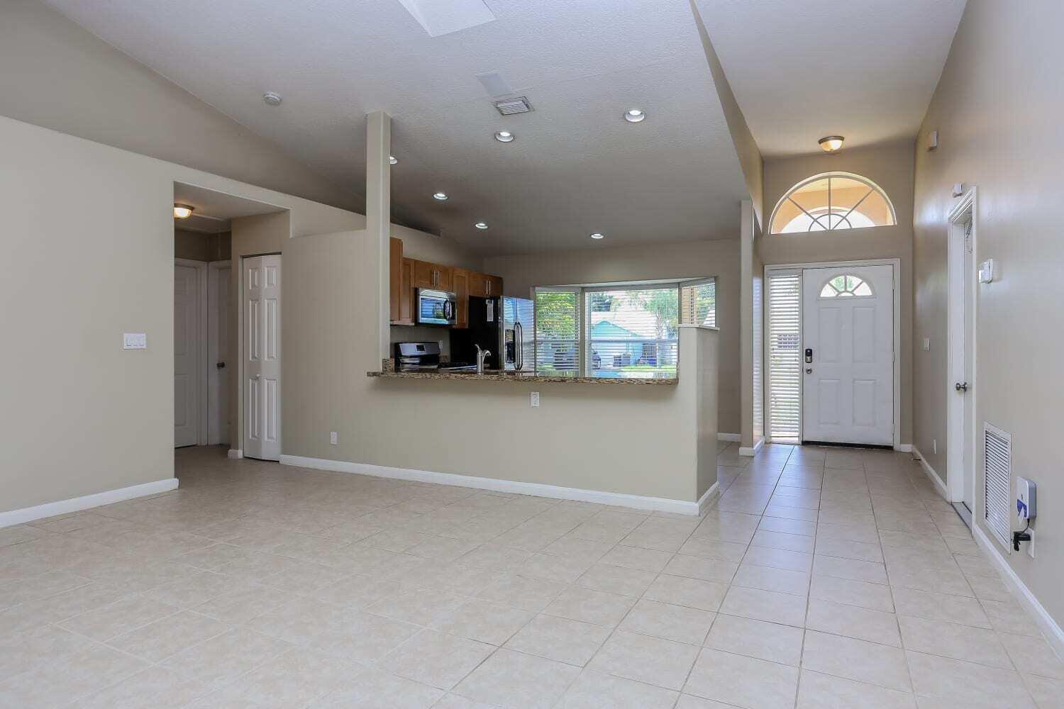 An open-concept living area with tile floors, a kitchen peninsula, and a front entryway — JUPITER, FL