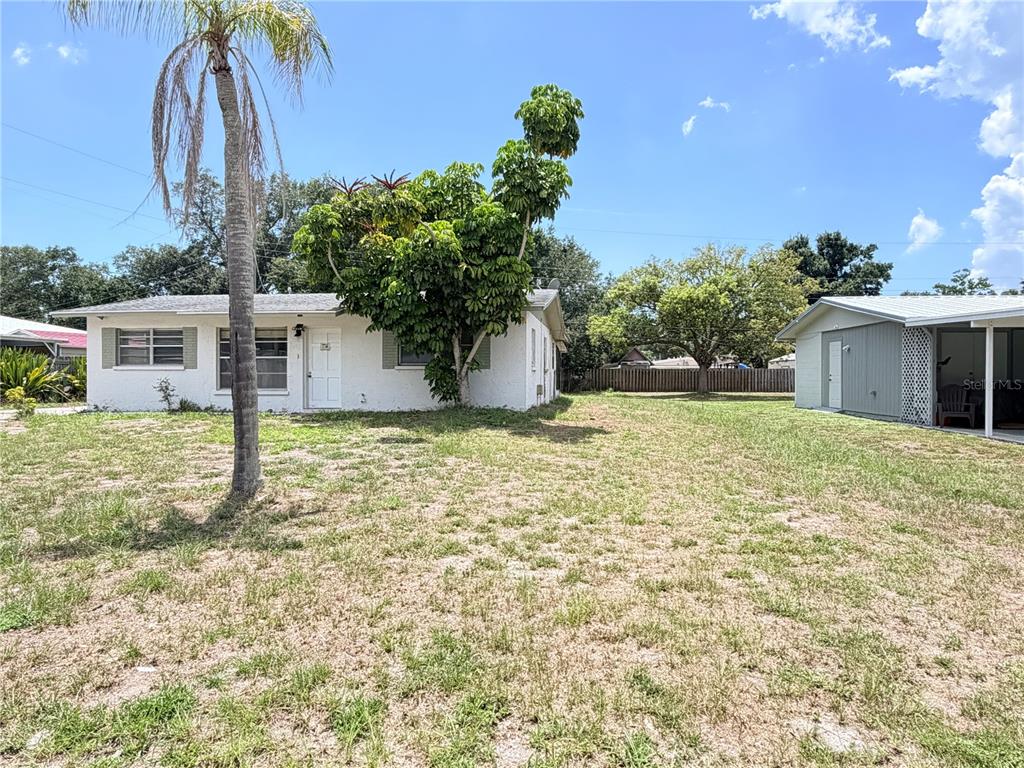 A white house with a palm tree and a large tree in the front yard — 3842 HAWKEYE CIRCLE, SARASOTA, FL