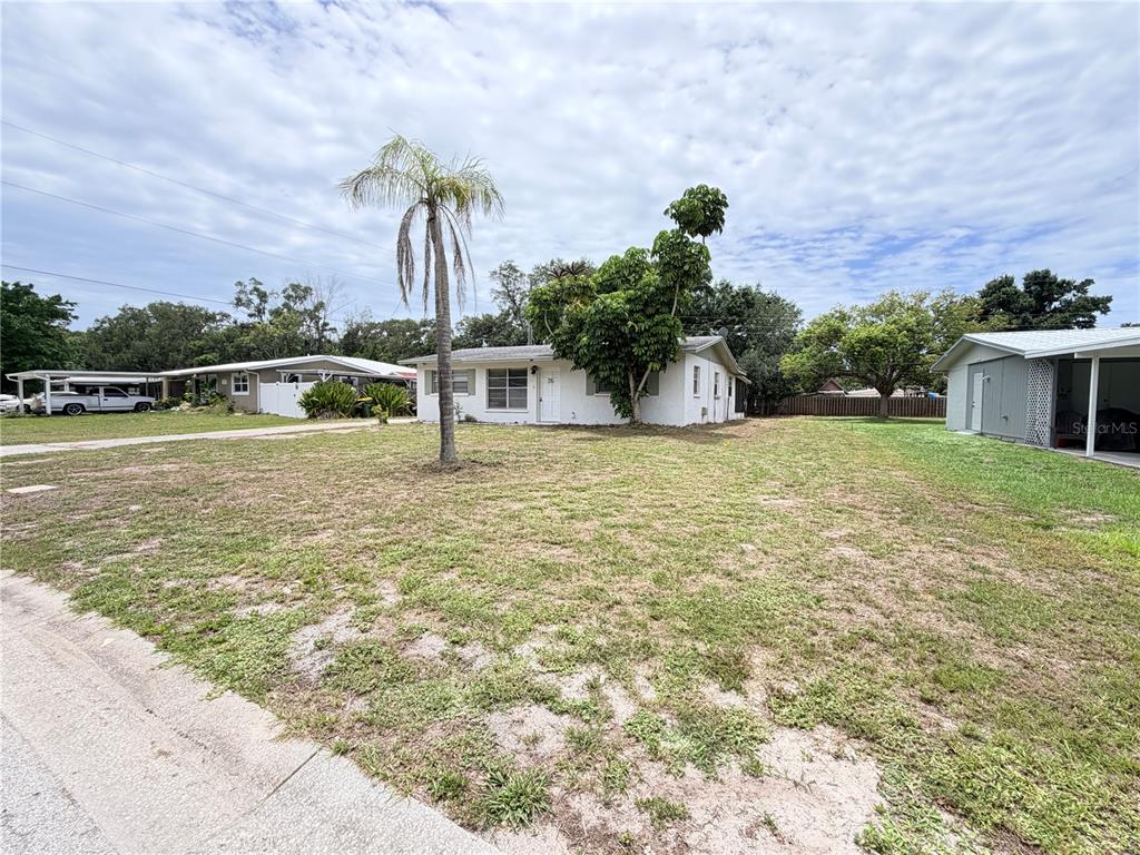 A white single-story house with a palm tree sits on a large, grassy lot — 3842 HAWKEYE CIRCLE, SARASOTA, FL