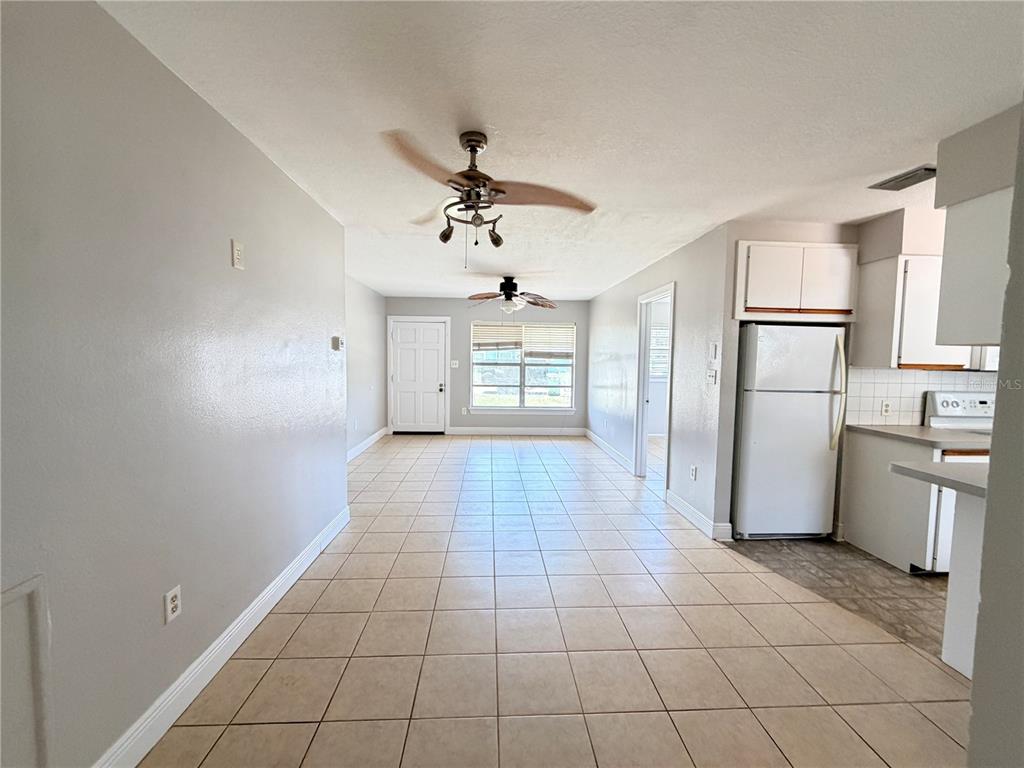 An open-concept living and dining area features light tile flooring, white walls, and ceiling fans — 3842 HAWKEYE CIRCLE, SARASOTA, FL