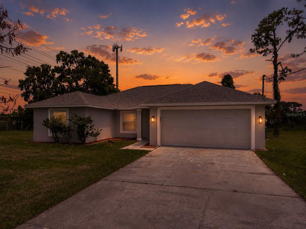 A single-story house with a two-car garage and a concrete driveway at sunset — 201 RONNIE CIRCLE, ORLANDO, FL