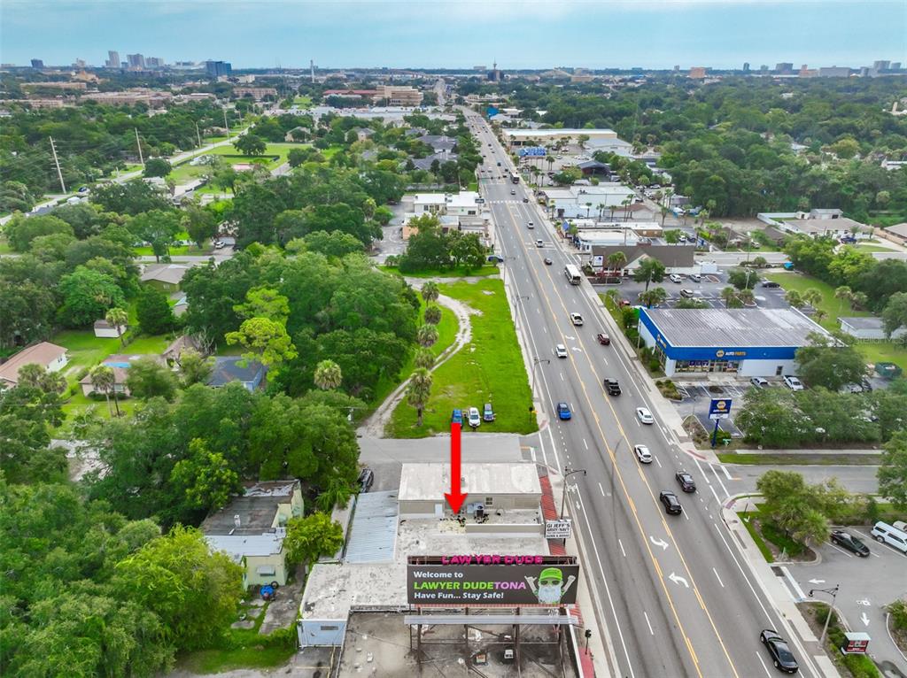 An aerial view shows a commercial building with a red arrow pointing to its roof — 936 W INTERNATIONAL SPEEDWAY BOULEVARD, DAYTONA BEACH, FL