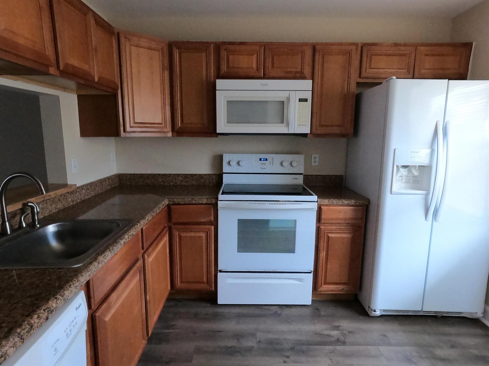 A kitchen features wood cabinets, granite countertops, and white appliances — 16363 Water Way, Delray Beach FL 33484, DELRAY BEACH, FL