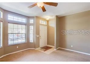 A living room with beige carpet, a ceiling fan, and a front door with windows — 6037 SCOTCHWOOD GLEN UNIT 8, ORLANDO, FL