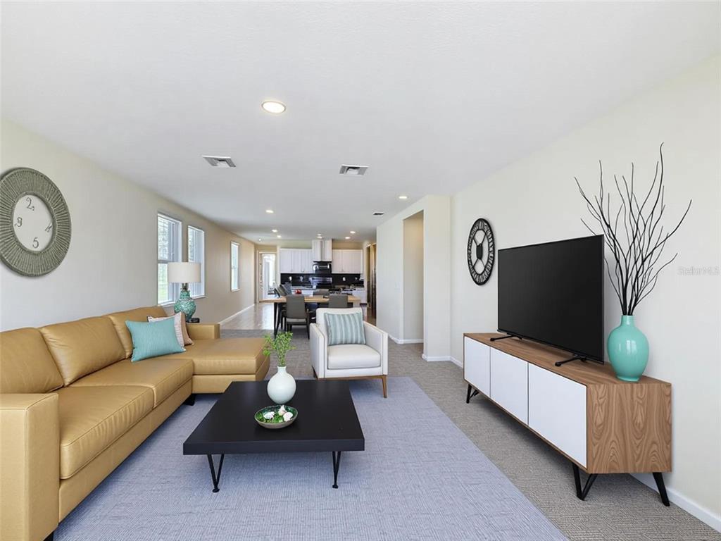 A living room with a tan sectional sofa, a television on a console, and an open kitchen — 520 KENNEDY DRIVE, LAKE ALFRED, FL