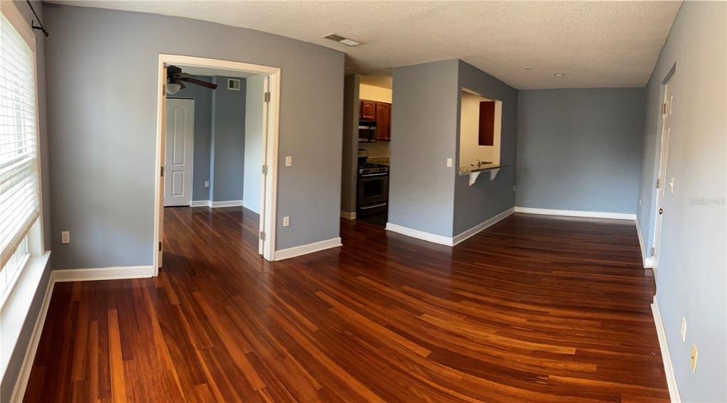 An interior view showing a living area with hardwood floors, blue walls, and a kitchen pass-through — 2047 DIXIE BELLE DRIVE UNIT 2047H, ORLANDO, FL